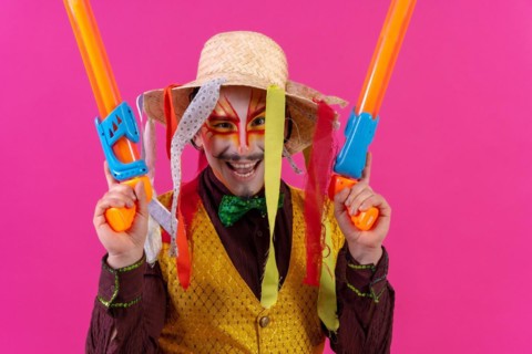 Clown with white facial makeup on a pink background