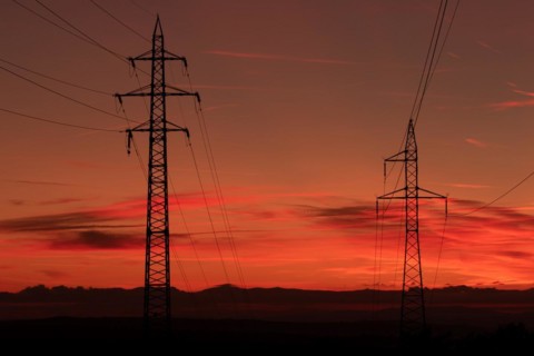 Silhouette of high voltage lines and transmission towers thru the Moravian field at sunrise