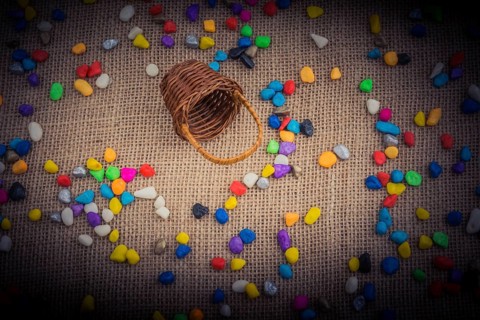 Basket and spilled pebbles on canvas background