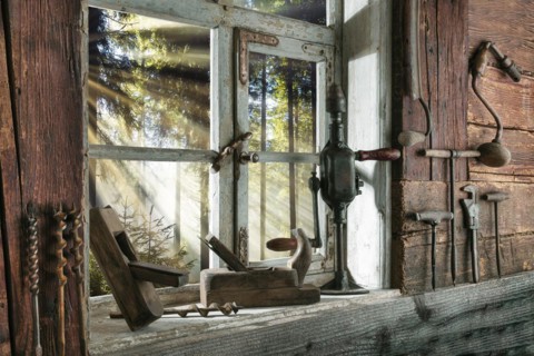 Rustic workshop with old tools and view out of the window into the forest
