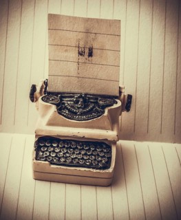 Retro syled tiny typewriter model on a paper background
