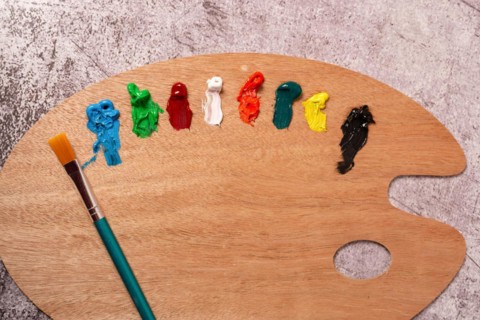 Top view of a palette with oil paints and brushes on a gray table