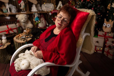 Grandmother sews a plush owl in Christmas arrangement. In studio