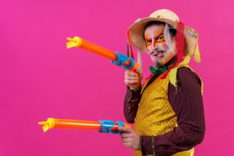 Clown with white facial makeup on a pink background