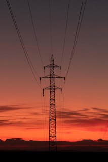 Silhouette of high voltage lines and transmission towers thru the Moravian field at sunrise