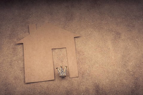 Litle model crown and paper house on a brown background