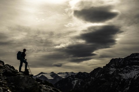 Climbers on rocks in backlight with cloudy sky in the background South Tyrolean mountains