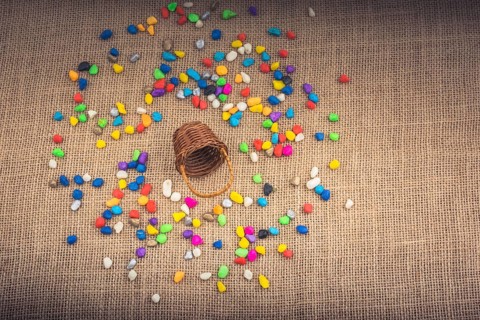 Basket and spilled pebbles on canvas background