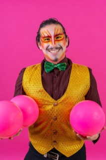 Portrait of clown with white facial makeup on a pink background
