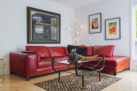 Red leather sectional sofa and black wrought iron with glass top coffee table in living room inside modern home