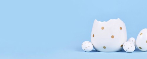 Banner with white easter eggs with golden dots and egg cup on blue background with copy space