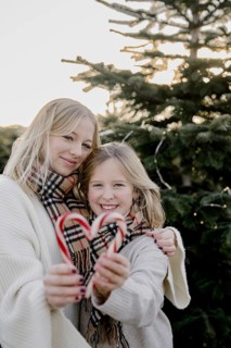 Two girls with candy cane hearts in front of a Christmas tree