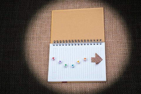 Love cubes and paper arrow on a notebook on canvas