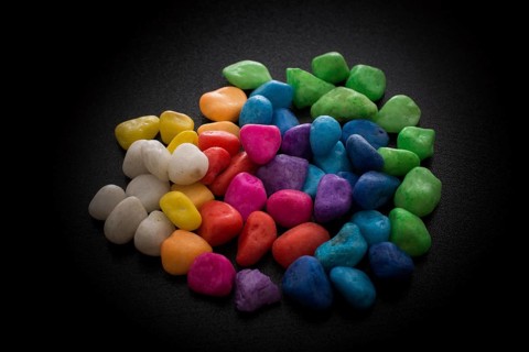 Pile of little colorful pebbles on black background