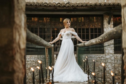 Beautiful rustic bride posing on wooden bridge full of candles