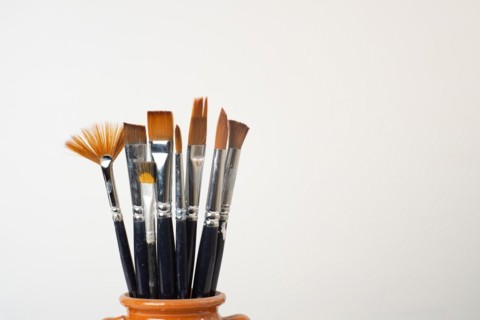 Earthenware jar with brushes isolated on a white background