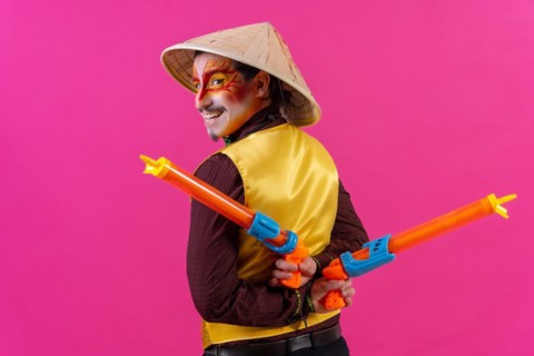 Portrait of a clown with white facial makeup on a pink background
