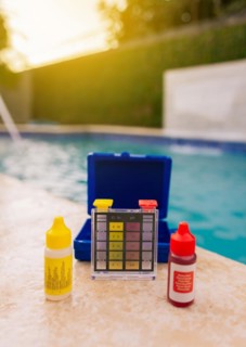 Chlorine test kit on the edge of the swimming pool Mini tester for pool maintenance. Water test kit for swimming pools