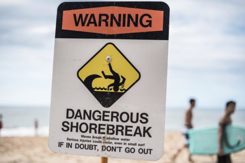 A dangerous shorebreak sign at the beach in the north shore of Oahu