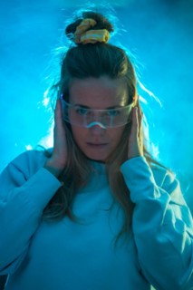 Confident young woman in futuristic glasses gesturing against a blue background