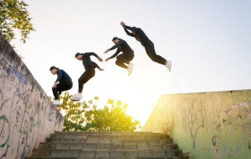 Athlete man doing parkour jumping walls. Low angle of man doing parkour at sunset. Latin guy doing parkour jumping walls.