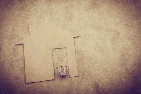 Litle model crown and paper house on a brown background