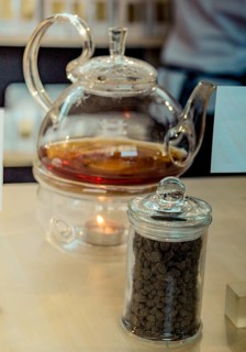 Herbal tea brewed in glass teapot and tea plant in a bottle
