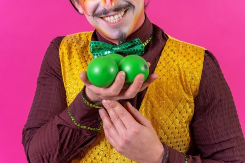 Portrait of clown with white facial makeup on a pink background