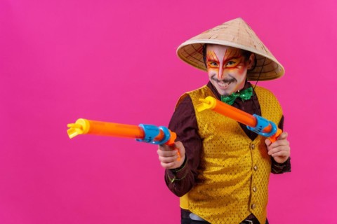 Clown with white facial makeup on a pink background