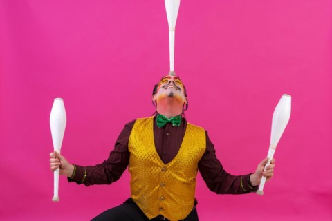 Clown with white facial makeup on a pink background