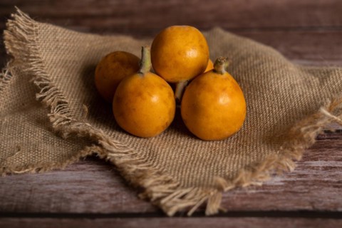 Group of organic nisperos on a raffia cloth on a wooden table