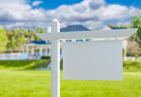 Blank real estate sign in front of new house