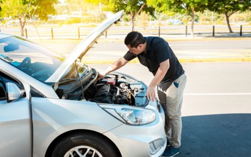 Driver checking the oil in his vehicle. Person checking the oil level of his car in the street. Driver inspecting car oil level