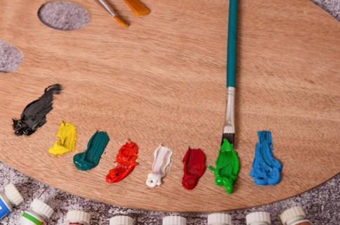 Top view of a palette with oil paints and brushes on a gray table