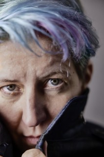 Androgynous woman with dyed hair pulls up the collar of her denim jacket