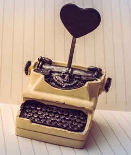 Retro syled tiny typewriter model on a paper background