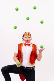 Smiling juggler juggling green balls isolated on white background