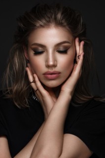 Portrait of a beautiful woman in a black dress with creative makeup in a fashion style. Beauty face. The photo was taken in a studio on a black background