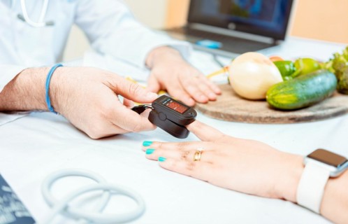 Close up of hands of nutritionist using pulse oximeter on patient finger. Nutritionist measuring oxygen pulse to patient