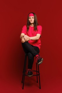 Young man sits on high chair with his leg on his leg