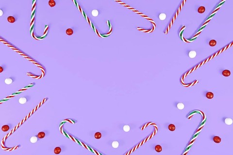 Christmas Candy canes forming frame around purple background with copy space