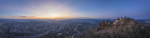 Panorama of the Hohentwiel castle ruins with the town of Singen am Hohentwiel in front of sunrise