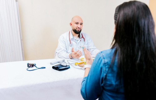 Back view of a female patient talking to the nutritionist. Smiling nutritionist explaining to a female patient