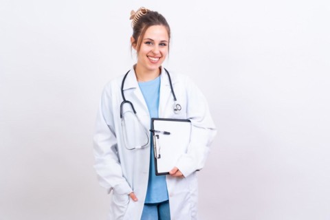 Happy beautiful female doctor in medical coat standing isolated on white