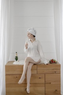 Portrait of an attractive woman with a towel on her head drinking champagne