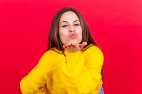 Photo portrait of a young woman blowing a kiss isolated on a red background