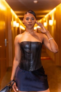 Medium shot of wealthy black ethnic woman posing in hotel room corridor