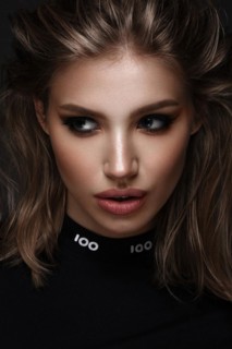 Portrait of a beautiful woman in a black dress with creative makeup in a fashion style. Beauty face. The photo was taken in a studio on a black background