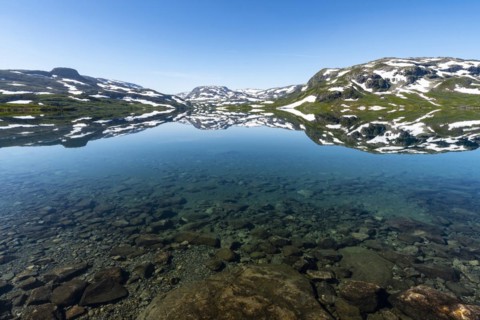 Reflection of partly snow-covered mountains in Lake Stavatn in Haukelifjell