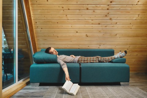 Man was reading a book in his wooden cabin in rainy day and fell asleep